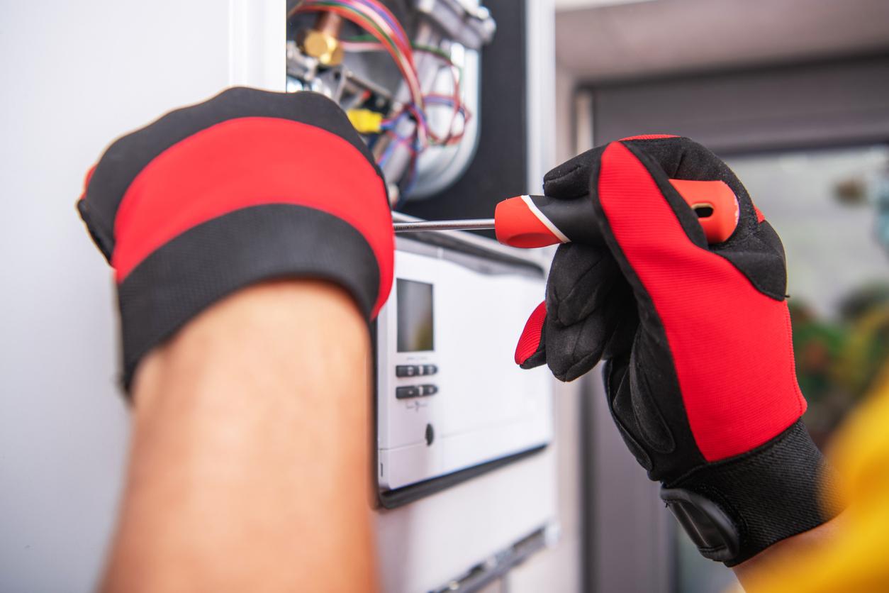HVAC technician’s gloved hand fixing an HVAC unit