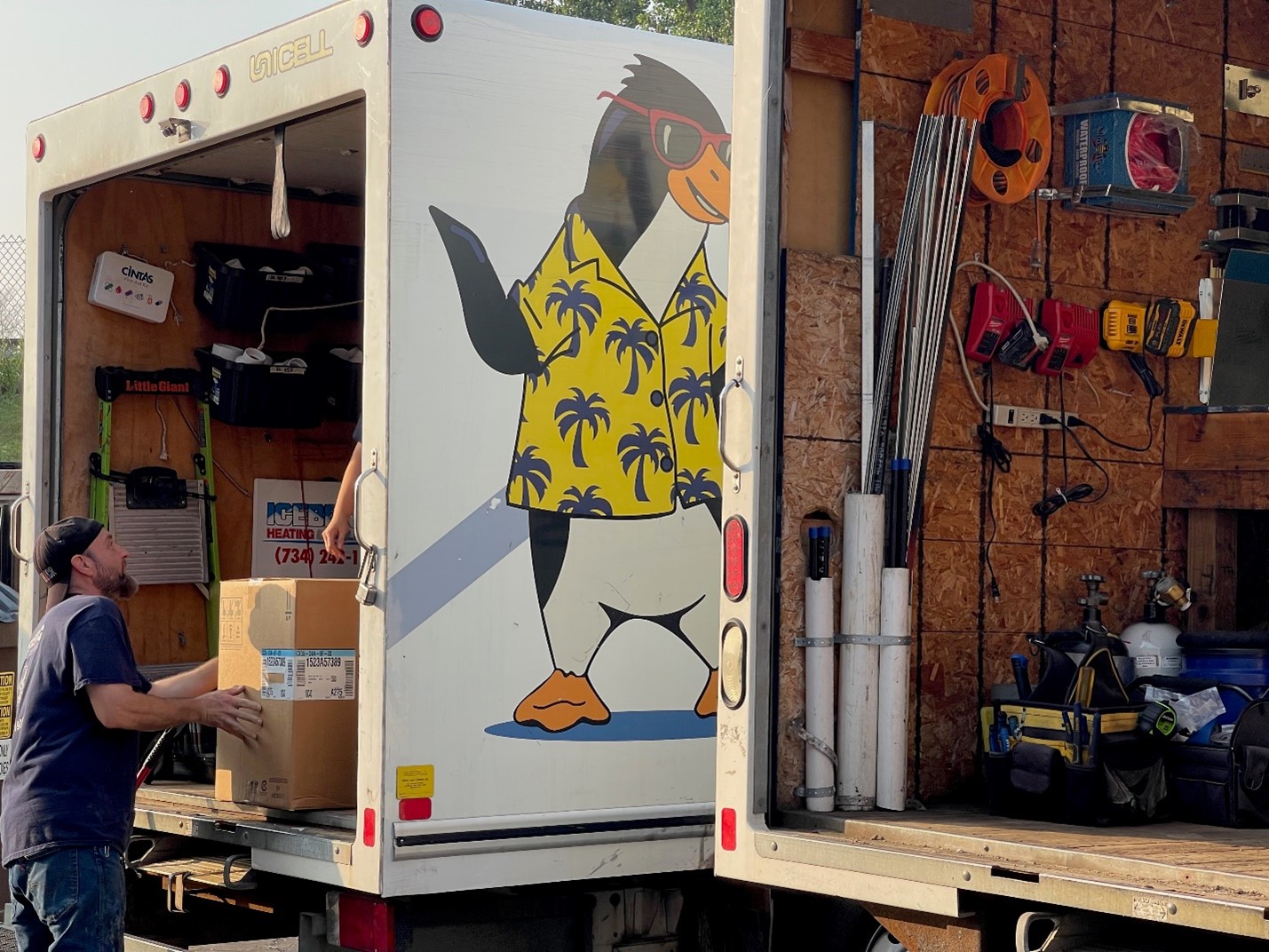 Iceberg Heating & Cooling technician unloading a truck with the image of the Iceberg penguin mascot