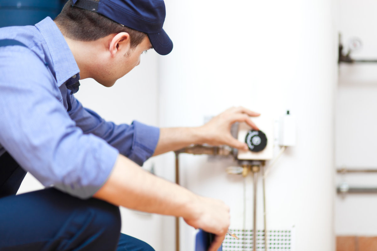 A plumber performing maintenance services on a water heater